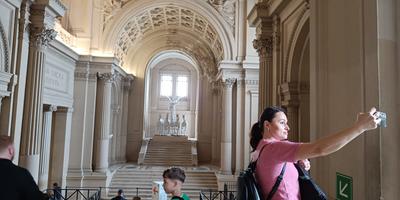 Turista che si scatta un selfie all'interno di una sala voltata ornata dei Musei Vaticani