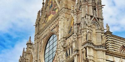 Obere Fassade der Kathedrale von Siena mit gotischen Spitzen, Rosettenfenster und goldenen Mosaiken