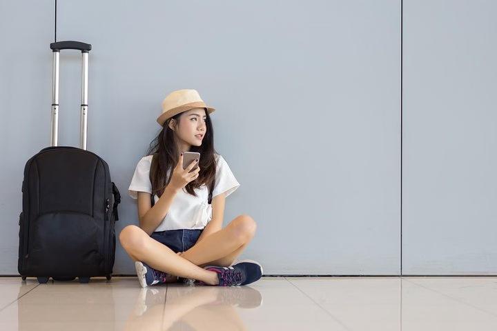 Femme assise à côté de sa valise
