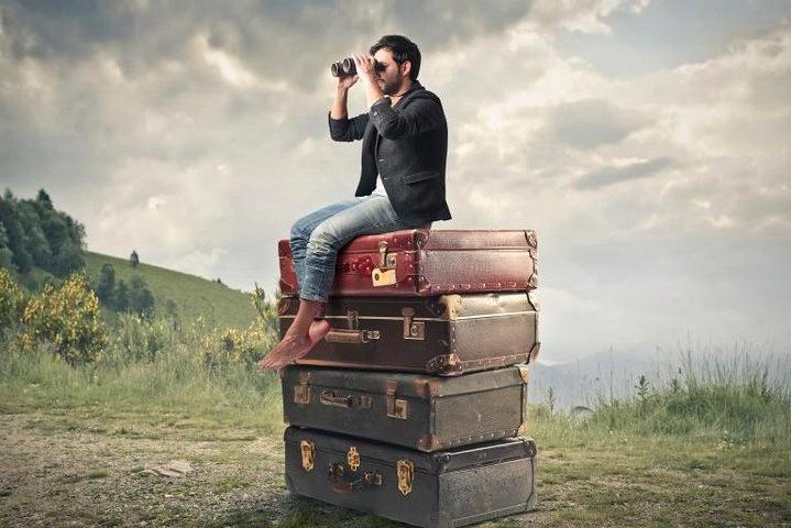 Homme debout sur plusieurs valises à la recherche d'une aventure